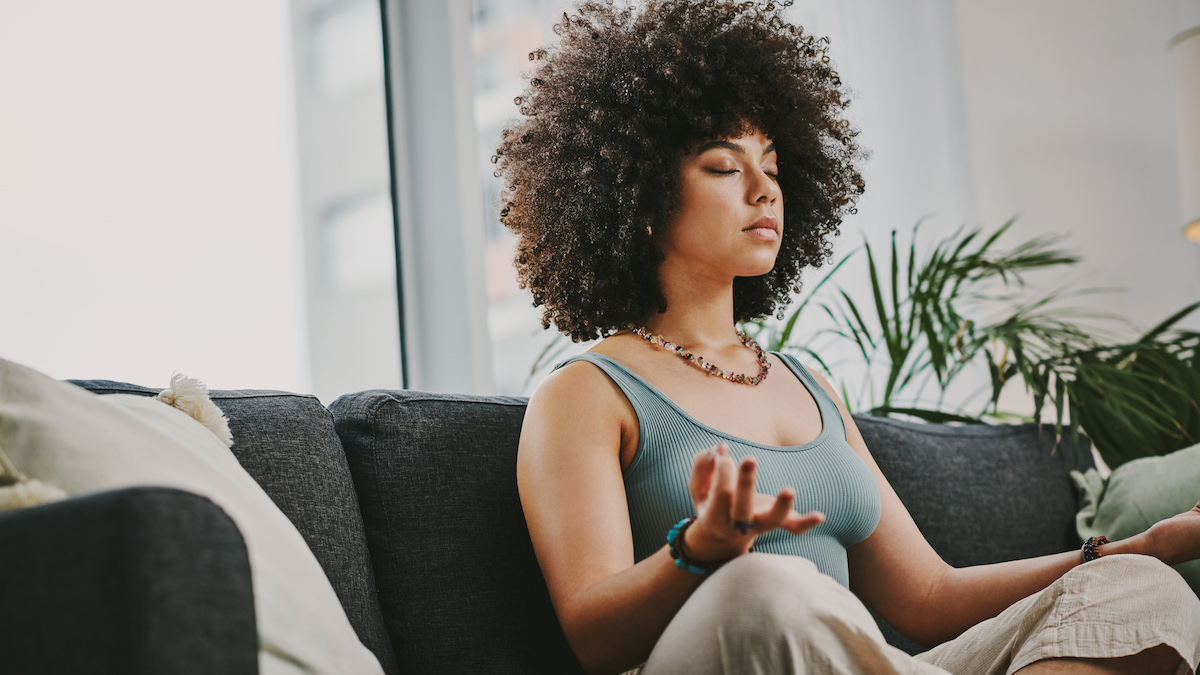 iIne Frau sitzt auf dem Sofa und macht Mudra Finger Yoga